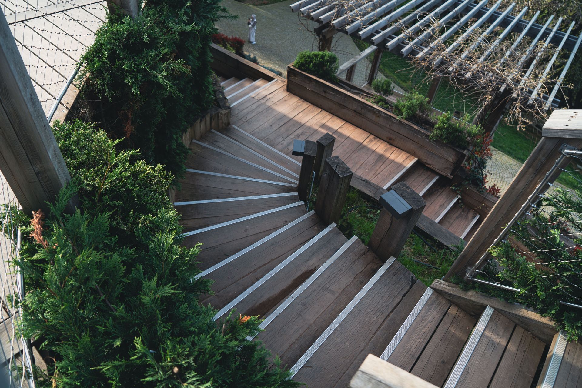 Explore the elegance of a wooden staircase surrounded by lush greenery in an outdoor garden.